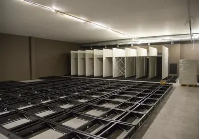 Mørkt rammeverk i firkanter ligger over hele golvet, lysegrå arkivreoler monteres oppå.