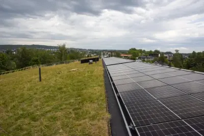 Taket på det regionale historiesenteret er mest dekket av gress, men med et felt av solcellepaneler øverst.