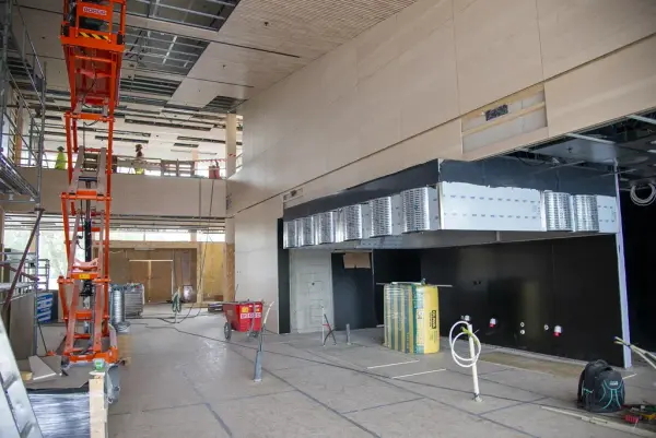 Til venstre er en oransje lift hevet så høyt den kan for at det skal kunne legges himling i lys ask, til høyre har avtrekkshetta i restaurantkjøkkenet kommet på plass.