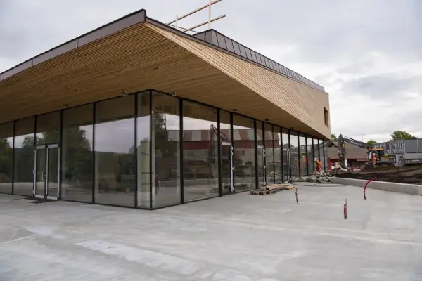 Støpt betongflate utenfor, takkonstruksjonen ser ut som en spiss og lang trekant som hviler på store vindusflater trukket godt innunder takskjegget.