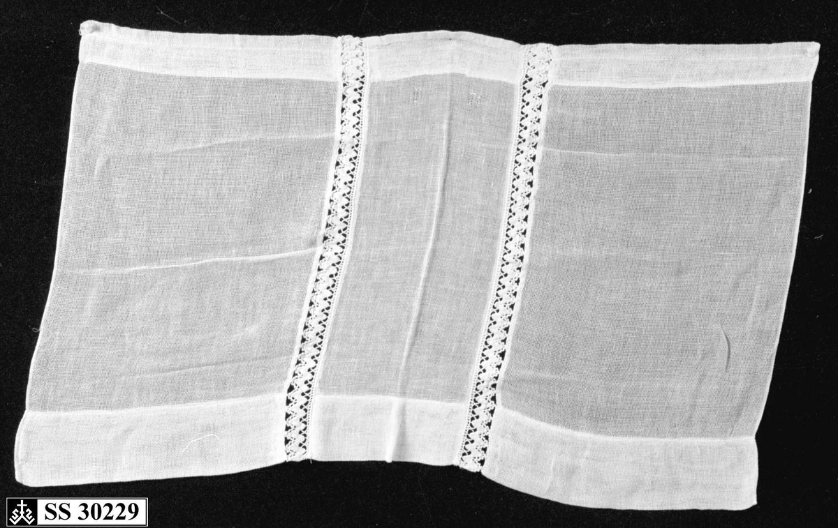 Hvit (gulnet) gardin med 2 innsydde blondebånd på midten.