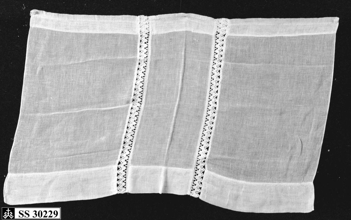 Hvit (gulnet) gardin med 2 innsydde blondebånd på midten.