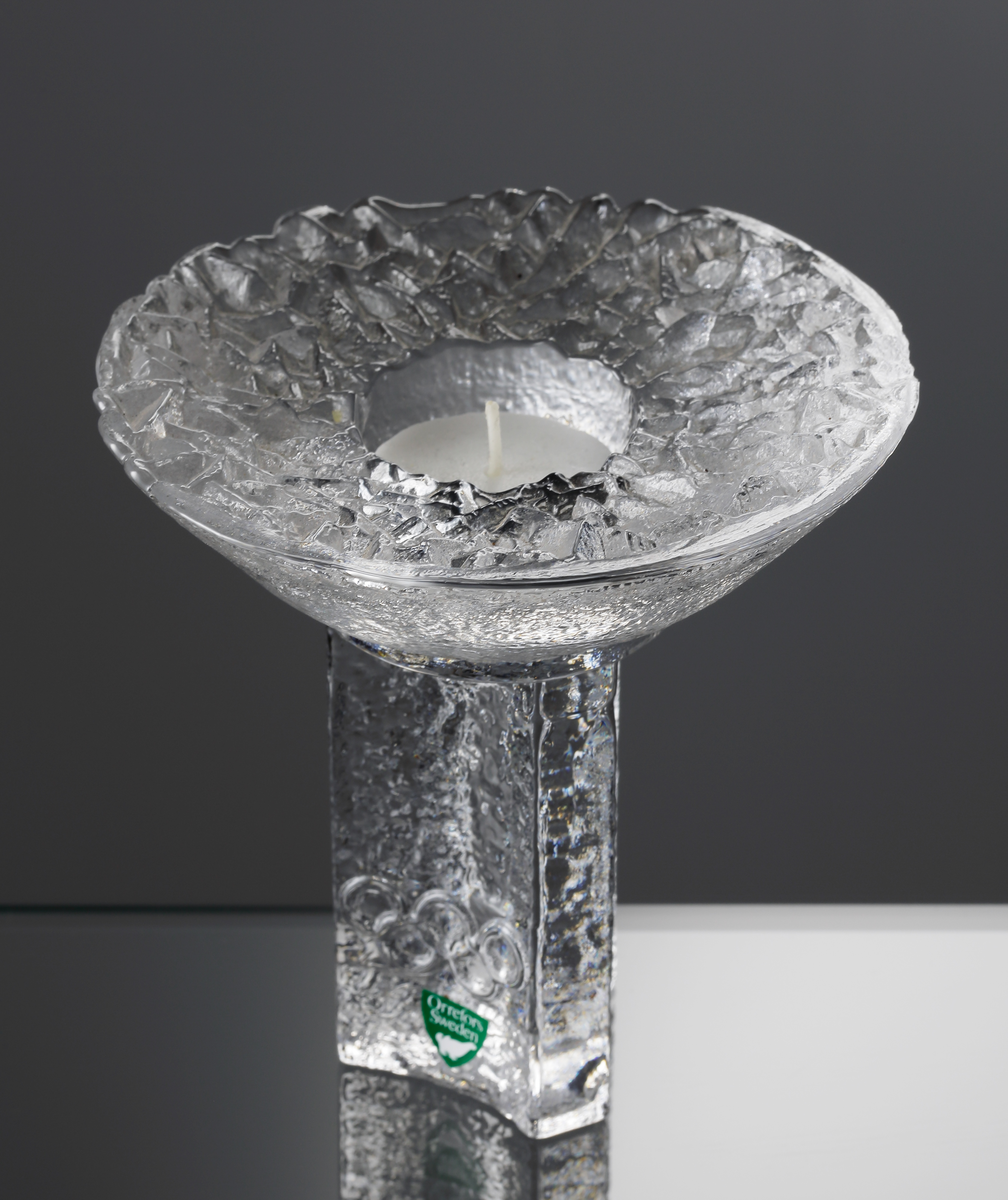 Glasskulptur i form av en OS-fackla, formgiven av Lars Hellsten 1985. 
Grön etikett med en vit orre (vilket markerar sekundaglas).