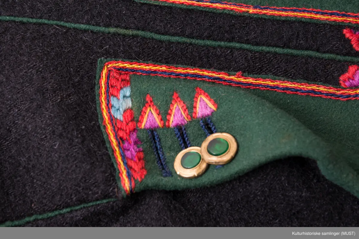 Bukse har fire hovedstykker i vadmel. Midtsøm framme og søm fra låket har innlagt grønn titte kant.
Den indre sømmen på bukse beinet går et stykke opp i baken før den møter baksømmen.
Bukse har smalt låk, belagt med grønnt klede med brodere og åtte knapphull og tre knapper. Tre knapper mangler. En kuleknapp i messing. To knapper i messing og grønn glass.
Lommeklaff oppstående (høyre side) belagt med grønnt klede med broderi. Grønn titte kant nede.
Lommefor lerret et firkantet stykke på sydd som lomme.
Nede, buksebein smale nederest bredde. Kantet med grønnt klede og opp splitt. Fire knapphull, fire messing kuleknapp og ullbroderi.