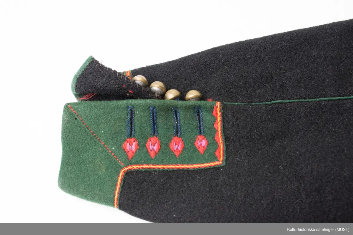 Bukse har fire hovedstykker i vadmel. Midtsøm framme og søm fra låket har innlagt grønn titte kant.
Den indre sømmen på bukse beinet går et stykke opp i baken før den møter baksømmen.
Bukse har smalt låk, belagt med grønnt klede med brodere og åtte knapphull og tre knapper. Tre knapper mangler. En kuleknapp i messing. To knapper i messing og grønn glass.
Lommeklaff oppstående (høyre side) belagt med grønnt klede med broderi. Grønn titte kant nede.
Lommefor lerret et firkantet stykke på sydd som lomme.
Nede, buksebein smale nederest bredde. Kantet med grønnt klede og opp splitt. Fire knapphull, fire messing kuleknapp og ullbroderi.