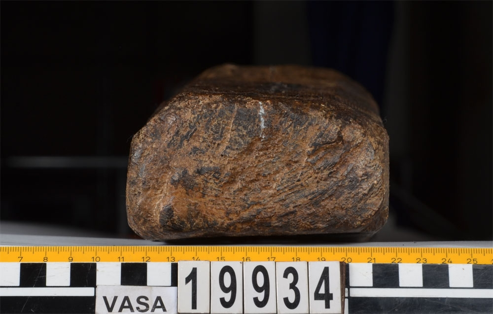 Bordklämma. Del av bordklämma bestående av den ena armen - eller käften. De ursprungliga kanterna och ändarna är i huvudsak väl bevarade. 840 mm från framänden finns  ett genomgående avlångt hål för tvärbrädan som håller ihop de två armarna. Eftersom märgen har lämnats kvar i ämnet har det bildats en märgspricka som löper längs översidans hela längd. Översidans kanter är fasade. Fasningens bredd är ca 25-30 mm. Ett genomgående, fyrkantigt spikhål med avtryck efter skalle på översidan, finns ca 55 mm från den smala ändens kant.  Verktygsspår på översidan, sannoligt av bilyxa. På den lätt välvda undersidan syns verktygsspår som troligen härrör  från en mer korteggad yxa. Det är gott om omotiverade och slumpvisa huggskador efter yxa, precis som om bordklämman vid något tillfälle har använts som huggkubbe. Föremålet är ganska oanfrätt.

För mer information se Dokumentationsblankett under Referenser – Länkade filer.