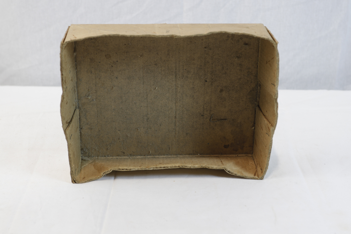 Del av pappeske. Esken har papirtape med logo. Brukt til enten oppbevaring eller innpakning av gullsmedgjenstander.