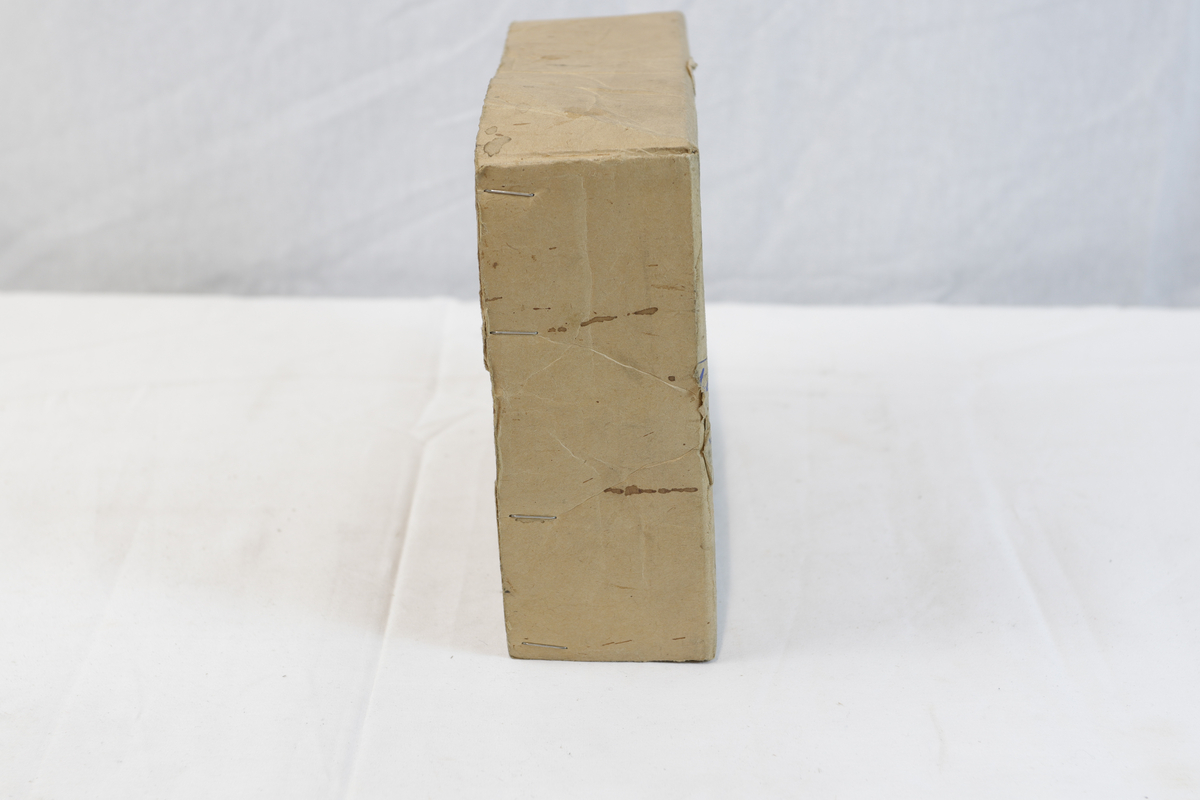 Del av pappeske. Esken har papirtape med logo. Brukt til enten oppbevaring eller innpakning av gullsmedgjenstander.