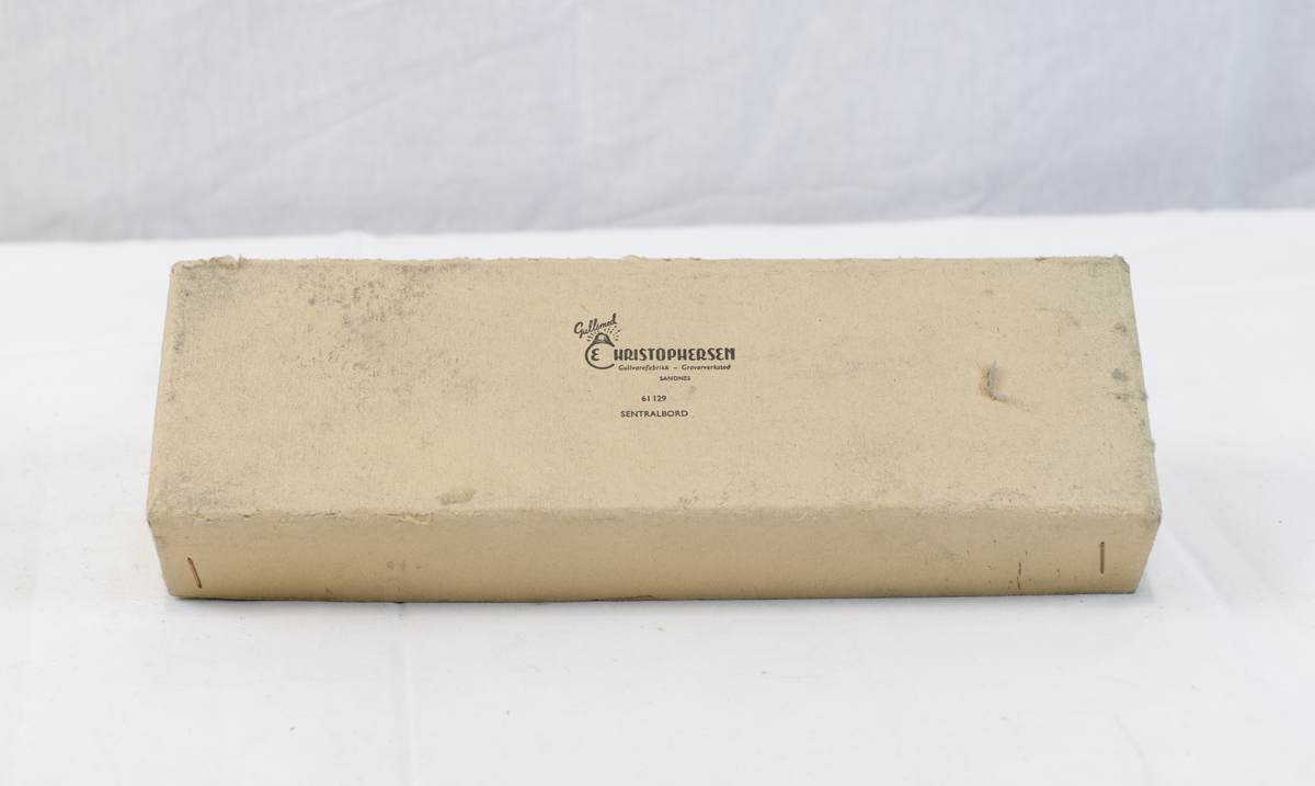 Avlang og kvadratisk pappeske. Pappesken har logo på lokk. Esken er trolig brukt til oppbevaring eller innpakning av gullsmedgjenstander.