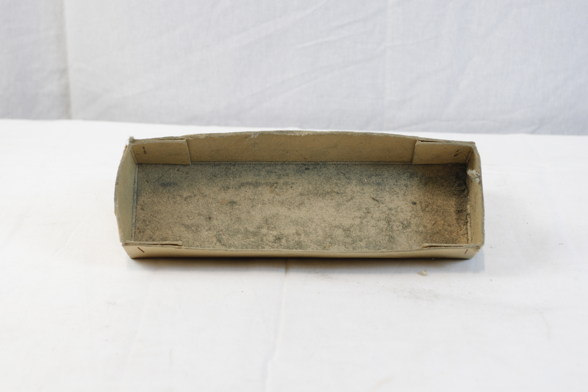 Avlang og kvadratisk pappeske. Pappesken har logo på lokk. Esken er trolig brukt til oppbevaring eller innpakning av gullsmedgjenstander.