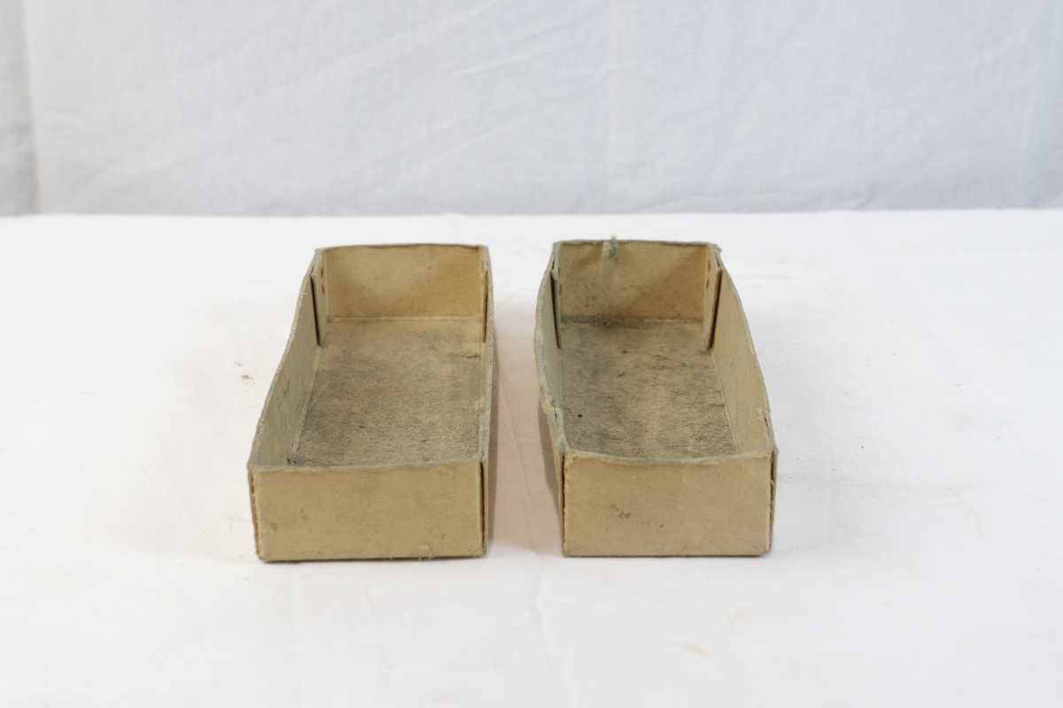 Avlang og kvadratisk pappeske. Pappesken har logo på lokk. Esken er trolig brukt til oppbevaring eller innpakning av gullsmedgjenstander.