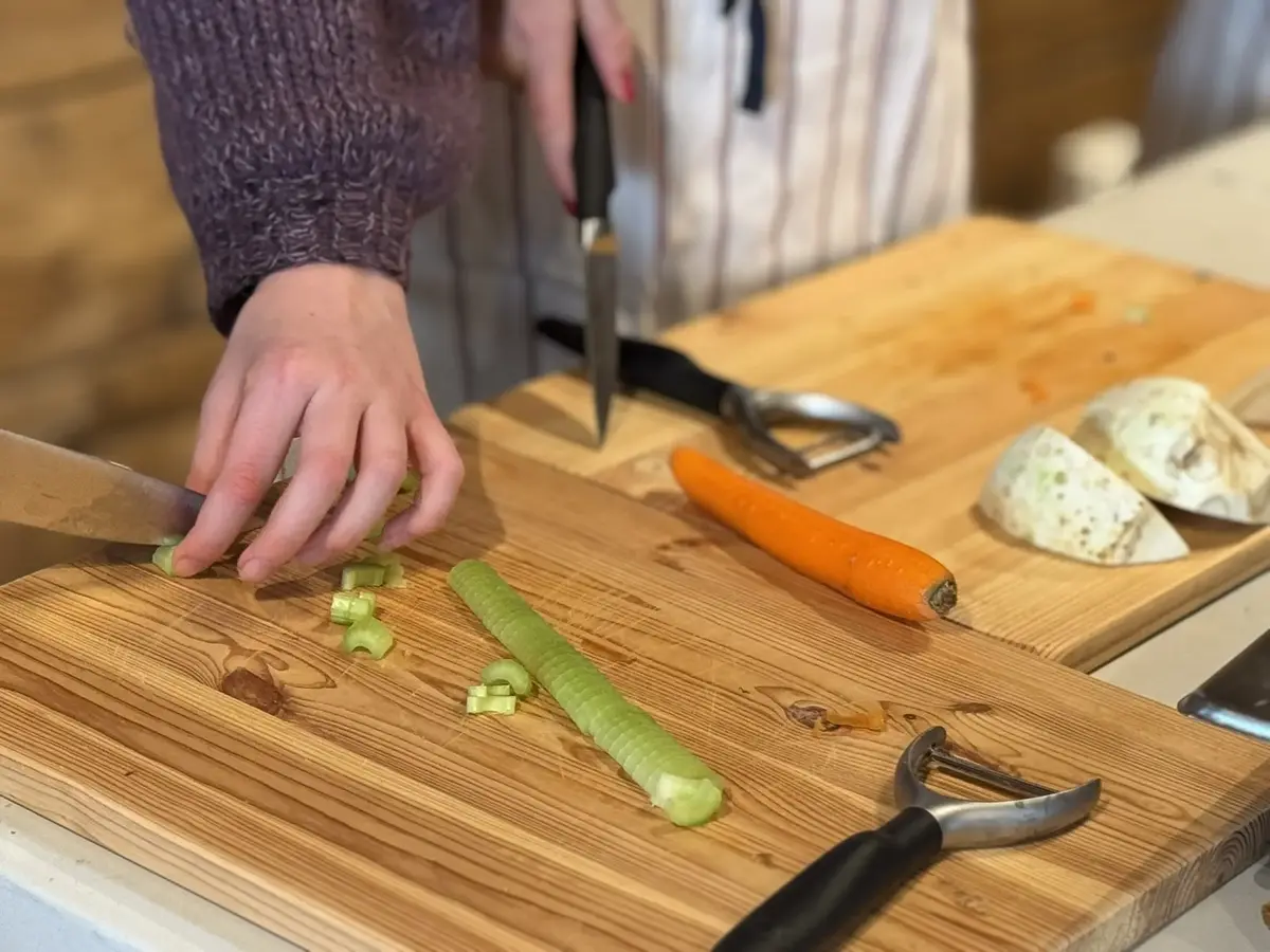 Barn kutter grønnsaker, purre, gulrot og selleri, ingredienser i fiskesuppen de lager