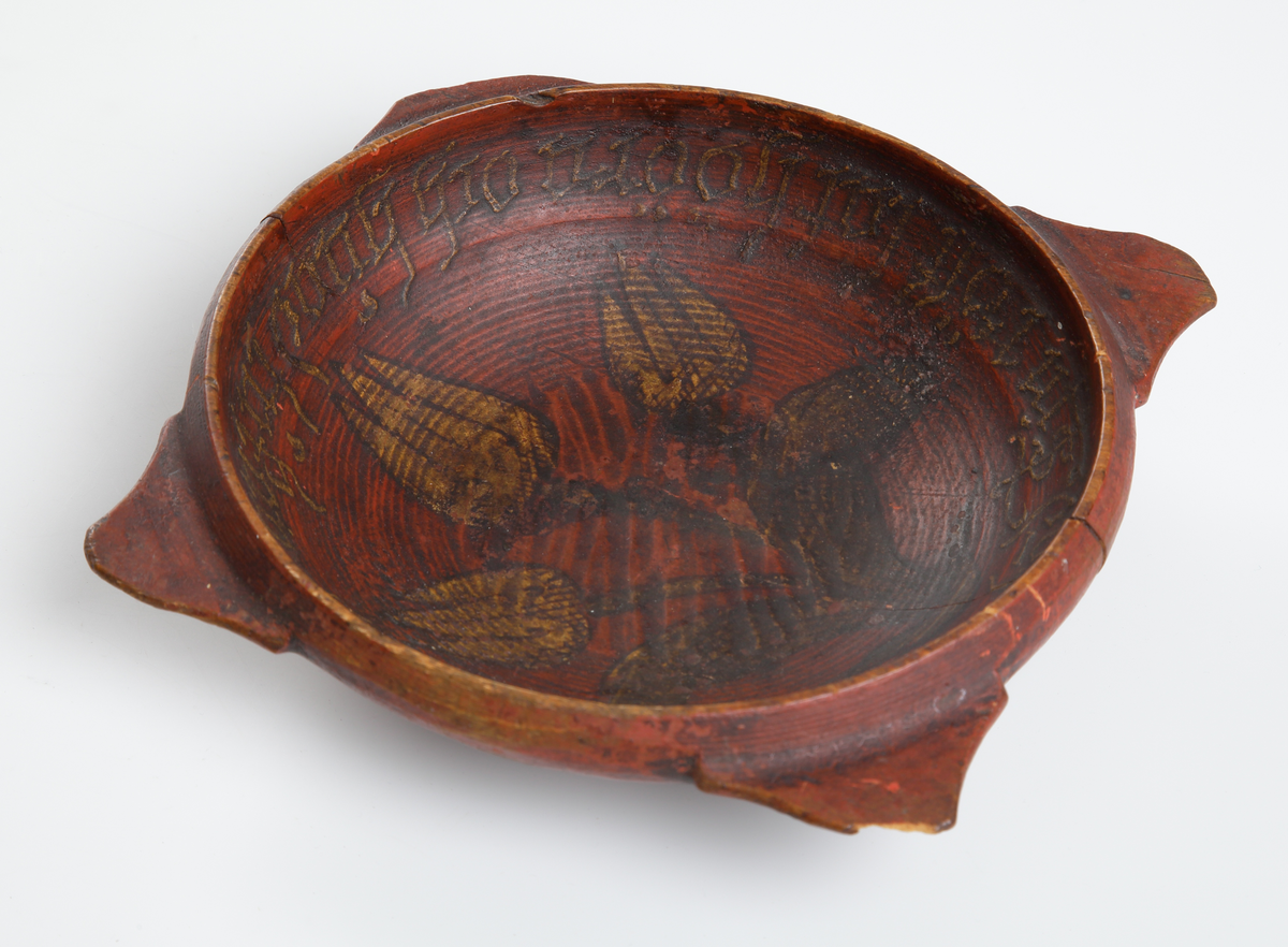 Snipaskål av trä. Rund skål med fyra platta handtag, jämt placerade runt mynningen. Med inskrift och målad dekor. 
Inskrivet i huvudbok 1867.