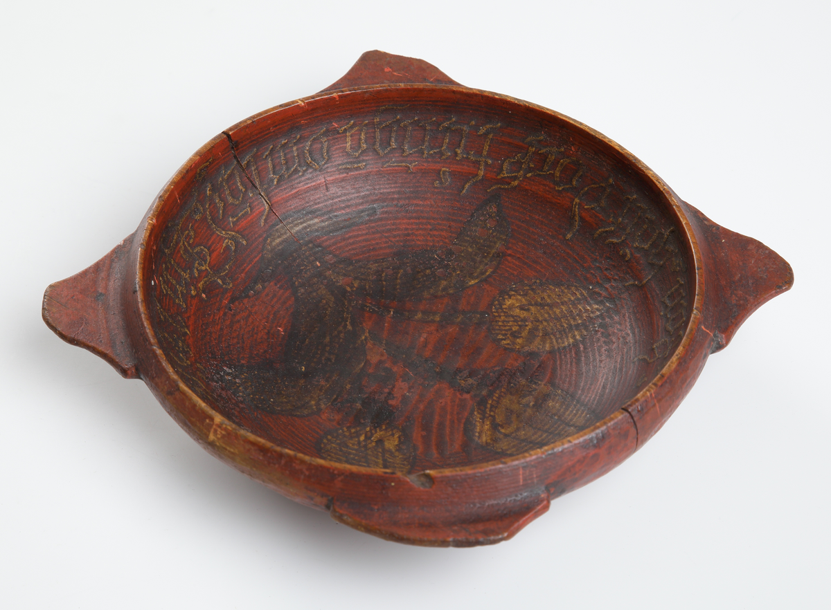 Snipaskål av trä. Rund skål med fyra platta handtag, jämt placerade runt mynningen. Med inskrift och målad dekor. 
Inskrivet i huvudbok 1867.