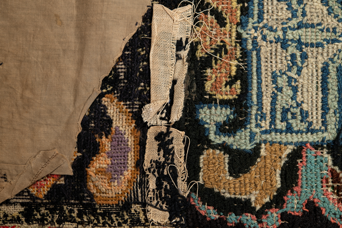 Linbotten med broderier i framför allt ull. Vissa detaljer troligen gjorda i silke. Lagningarna utförda i ull och bomull. Broderiet gjort i korsstygn. De äldsta delarna (bården) är gjorda i olika stora stygn varför ytans karaktär varierar. Mönster som påminner om pompeijansk stil med bland annat kartusher, urnor och växtornament. Mittpartiet inramat med roccaier eller akantusblad, blombotten med liljor och rosor samt vinrankor. Längst ena långsidan även inslag av korall. Hörn med spiralformade blomstergirlanger, dessa med drag av folkligt broderi.
Brunsvart botten, ojämt blekt. Merparten beigegröna nyanser på växtornamenten. Blåa och röda inslag där vissa röda delar skulle kunna vara anilinfärg, troligen i övrigt växtfärg.