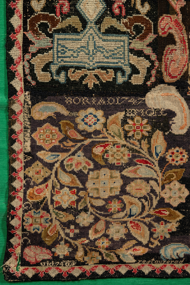 Linbotten med broderier i framför allt ull. Vissa detaljer troligen gjorda i silke. Lagningarna utförda i ull och bomull. Broderiet gjort i korsstygn. De äldsta delarna (bården) är gjorda i olika stora stygn varför ytans karaktär varierar. Mönster som påminner om pompeijansk stil med bland annat kartusher, urnor och växtornament. Mittpartiet inramat med roccaier eller akantusblad, blombotten med liljor och rosor samt vinrankor. Längst ena långsidan även inslag av korall. Hörn med spiralformade blomstergirlanger, dessa med drag av folkligt broderi.
Brunsvart botten, ojämt blekt. Merparten beigegröna nyanser på växtornamenten. Blåa och röda inslag där vissa röda delar skulle kunna vara anilinfärg, troligen i övrigt växtfärg.