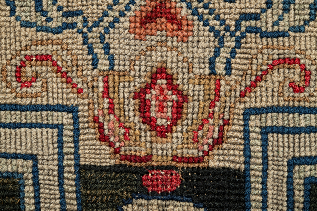 Linbotten med broderier i framför allt ull. Vissa detaljer troligen gjorda i silke. Lagningarna utförda i ull och bomull. Broderiet gjort i korsstygn. De äldsta delarna (bården) är gjorda i olika stora stygn varför ytans karaktär varierar. Mönster som påminner om pompeijansk stil med bland annat kartusher, urnor och växtornament. Mittpartiet inramat med roccaier eller akantusblad, blombotten med liljor och rosor samt vinrankor. Längst ena långsidan även inslag av korall. Hörn med spiralformade blomstergirlanger, dessa med drag av folkligt broderi.
Brunsvart botten, ojämt blekt. Merparten beigegröna nyanser på växtornamenten. Blåa och röda inslag där vissa röda delar skulle kunna vara anilinfärg, troligen i övrigt växtfärg.