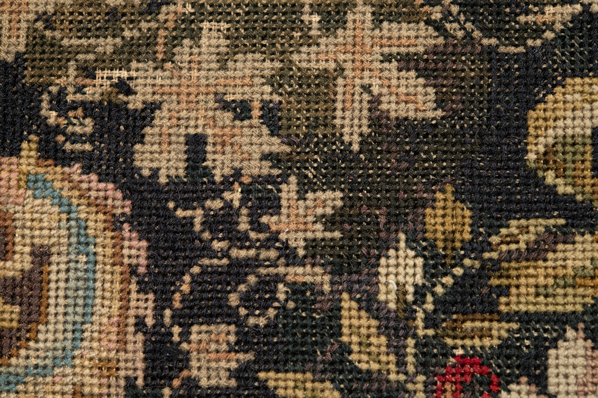 Linbotten med broderier i framför allt ull. Vissa detaljer troligen gjorda i silke. Lagningarna utförda i ull och bomull. Broderiet gjort i korsstygn. De äldsta delarna (bården) är gjorda i olika stora stygn varför ytans karaktär varierar. Mönster som påminner om pompeijansk stil med bland annat kartusher, urnor och växtornament. Mittpartiet inramat med roccaier eller akantusblad, blombotten med liljor och rosor samt vinrankor. Längst ena långsidan även inslag av korall. Hörn med spiralformade blomstergirlanger, dessa med drag av folkligt broderi.
Brunsvart botten, ojämt blekt. Merparten beigegröna nyanser på växtornamenten. Blåa och röda inslag där vissa röda delar skulle kunna vara anilinfärg, troligen i övrigt växtfärg.