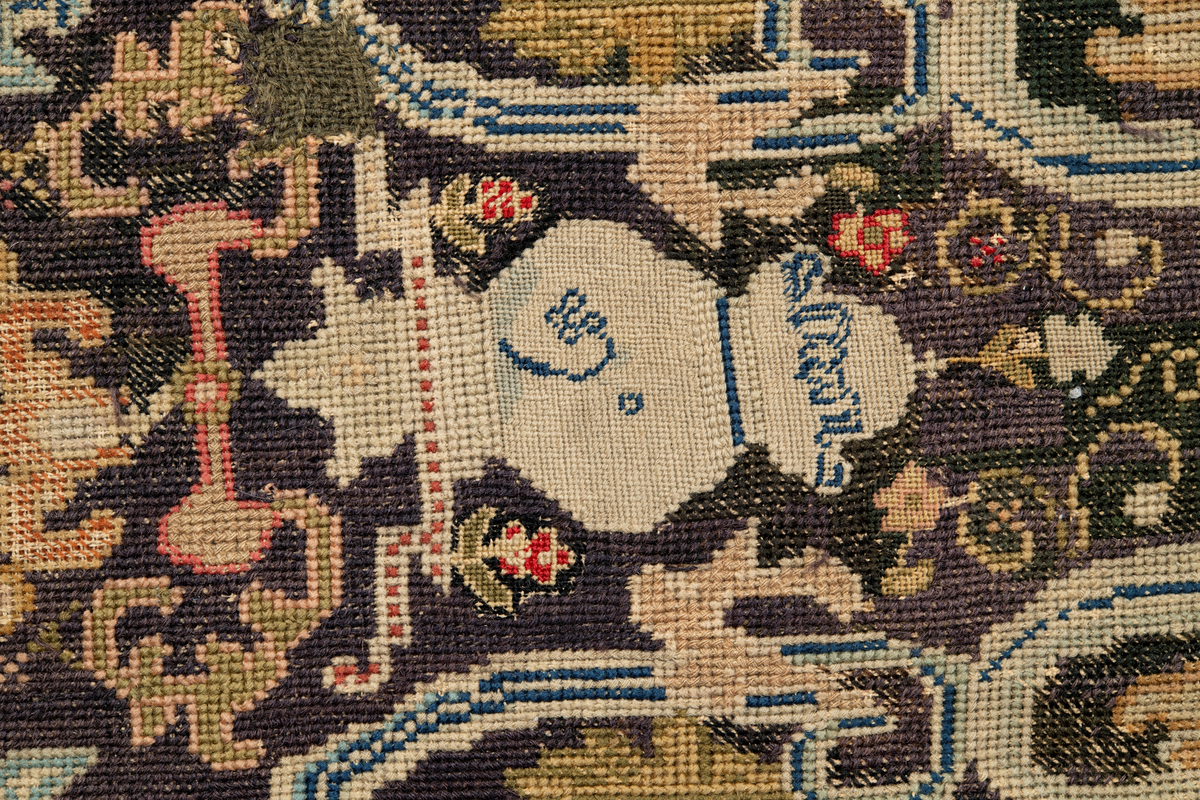 Linbotten med broderier i framför allt ull. Vissa detaljer troligen gjorda i silke. Lagningarna utförda i ull och bomull. Broderiet gjort i korsstygn. De äldsta delarna (bården) är gjorda i olika stora stygn varför ytans karaktär varierar. Mönster som påminner om pompeijansk stil med bland annat kartusher, urnor och växtornament. Mittpartiet inramat med roccaier eller akantusblad, blombotten med liljor och rosor samt vinrankor. Längst ena långsidan även inslag av korall. Hörn med spiralformade blomstergirlanger, dessa med drag av folkligt broderi.
Brunsvart botten, ojämt blekt. Merparten beigegröna nyanser på växtornamenten. Blåa och röda inslag där vissa röda delar skulle kunna vara anilinfärg, troligen i övrigt växtfärg.