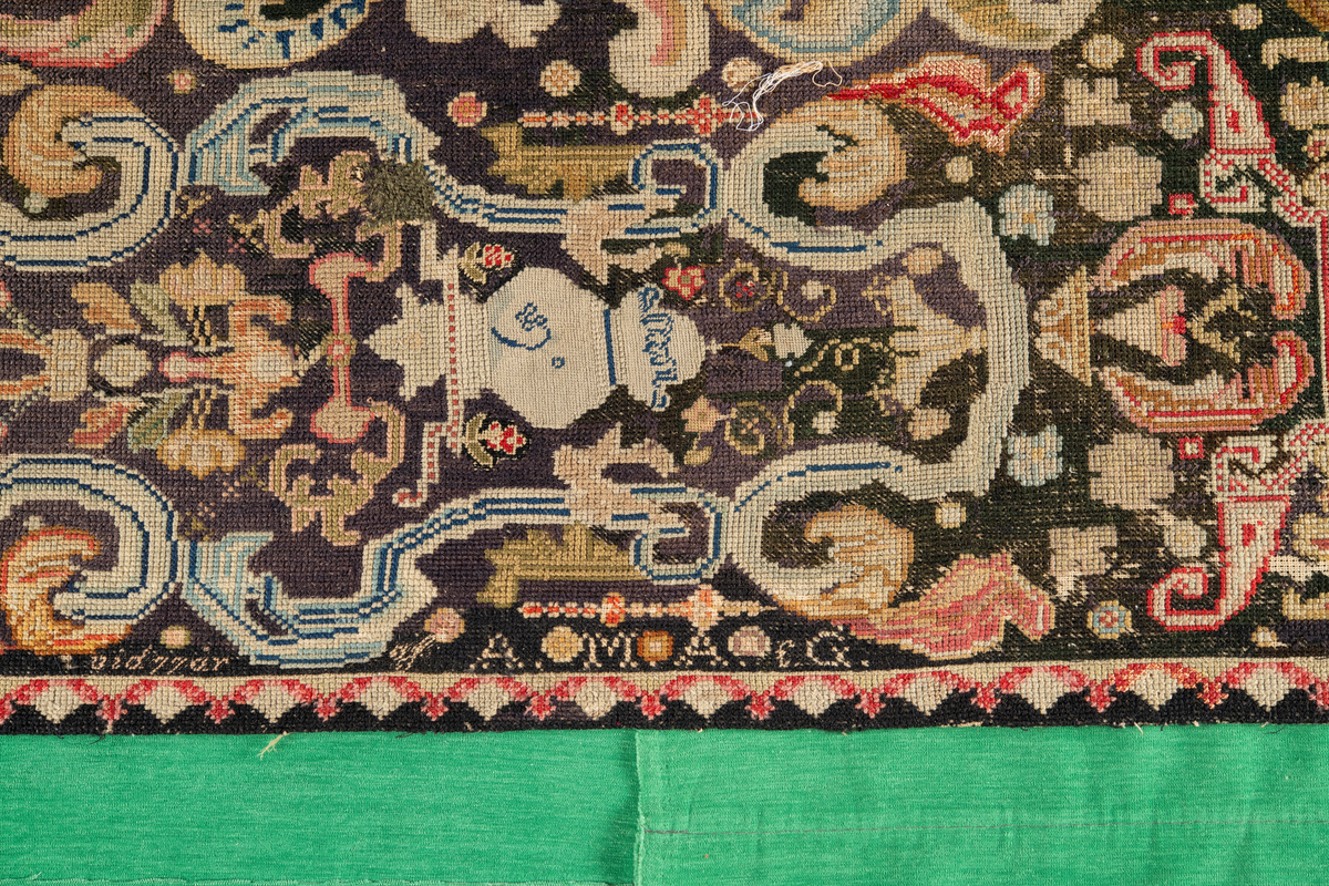 Linbotten med broderier i framför allt ull. Vissa detaljer troligen gjorda i silke. Lagningarna utförda i ull och bomull. Broderiet gjort i korsstygn. De äldsta delarna (bården) är gjorda i olika stora stygn varför ytans karaktär varierar. Mönster som påminner om pompeijansk stil med bland annat kartusher, urnor och växtornament. Mittpartiet inramat med roccaier eller akantusblad, blombotten med liljor och rosor samt vinrankor. Längst ena långsidan även inslag av korall. Hörn med spiralformade blomstergirlanger, dessa med drag av folkligt broderi.
Brunsvart botten, ojämt blekt. Merparten beigegröna nyanser på växtornamenten. Blåa och röda inslag där vissa röda delar skulle kunna vara anilinfärg, troligen i övrigt växtfärg.