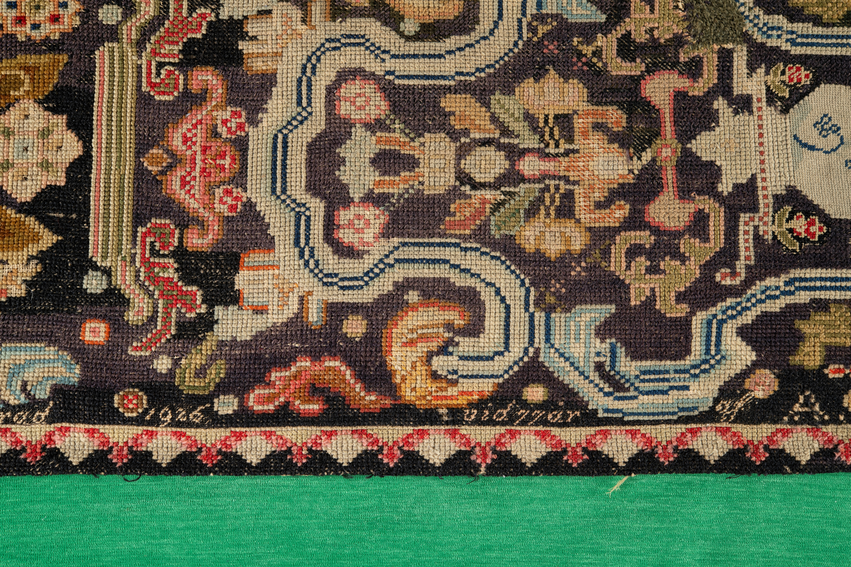 Linbotten med broderier i framför allt ull. Vissa detaljer troligen gjorda i silke. Lagningarna utförda i ull och bomull. Broderiet gjort i korsstygn. De äldsta delarna (bården) är gjorda i olika stora stygn varför ytans karaktär varierar. Mönster som påminner om pompeijansk stil med bland annat kartusher, urnor och växtornament. Mittpartiet inramat med roccaier eller akantusblad, blombotten med liljor och rosor samt vinrankor. Längst ena långsidan även inslag av korall. Hörn med spiralformade blomstergirlanger, dessa med drag av folkligt broderi.
Brunsvart botten, ojämt blekt. Merparten beigegröna nyanser på växtornamenten. Blåa och röda inslag där vissa röda delar skulle kunna vara anilinfärg, troligen i övrigt växtfärg.