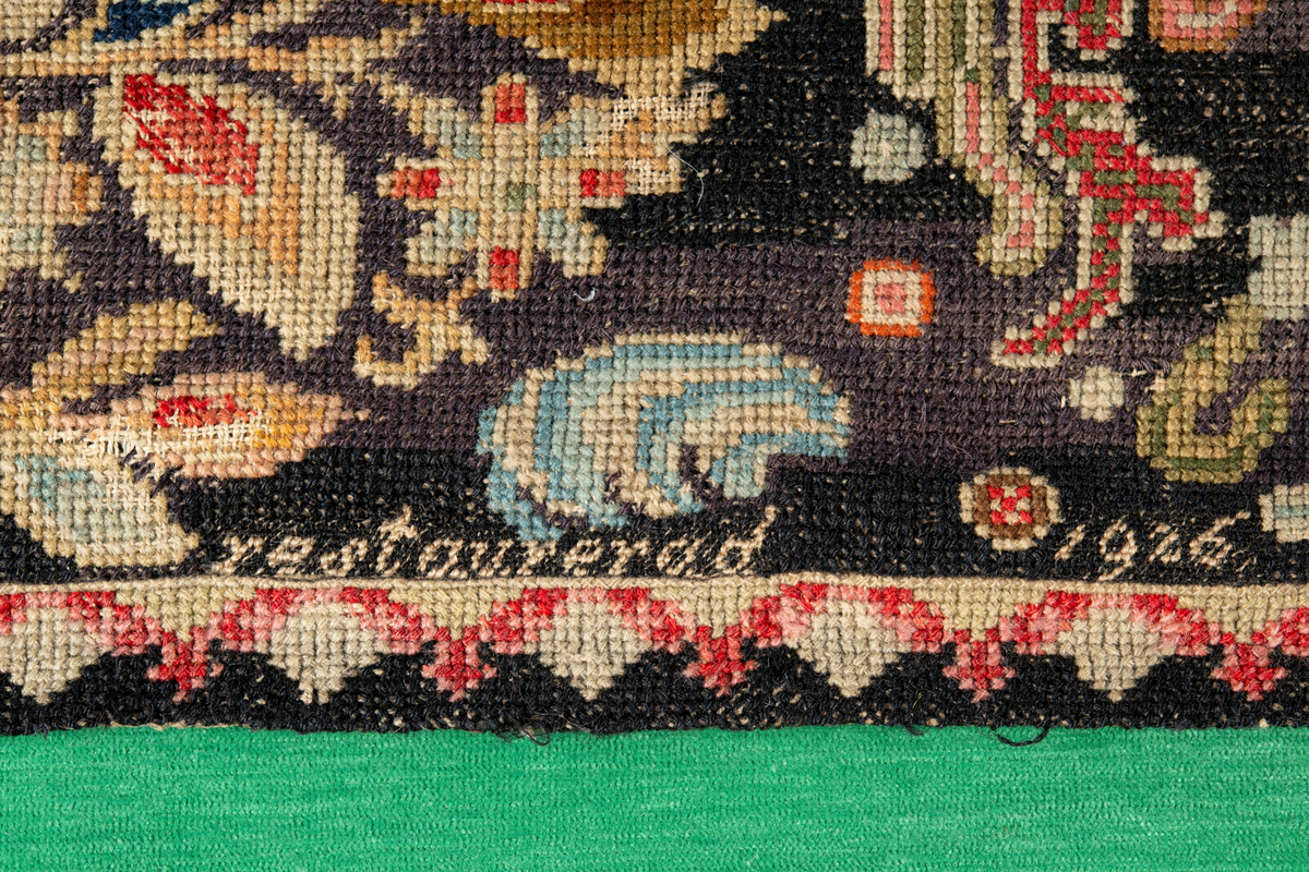 Linbotten med broderier i framför allt ull. Vissa detaljer troligen gjorda i silke. Lagningarna utförda i ull och bomull. Broderiet gjort i korsstygn. De äldsta delarna (bården) är gjorda i olika stora stygn varför ytans karaktär varierar. Mönster som påminner om pompeijansk stil med bland annat kartusher, urnor och växtornament. Mittpartiet inramat med roccaier eller akantusblad, blombotten med liljor och rosor samt vinrankor. Längst ena långsidan även inslag av korall. Hörn med spiralformade blomstergirlanger, dessa med drag av folkligt broderi.
Brunsvart botten, ojämt blekt. Merparten beigegröna nyanser på växtornamenten. Blåa och röda inslag där vissa röda delar skulle kunna vara anilinfärg, troligen i övrigt växtfärg.