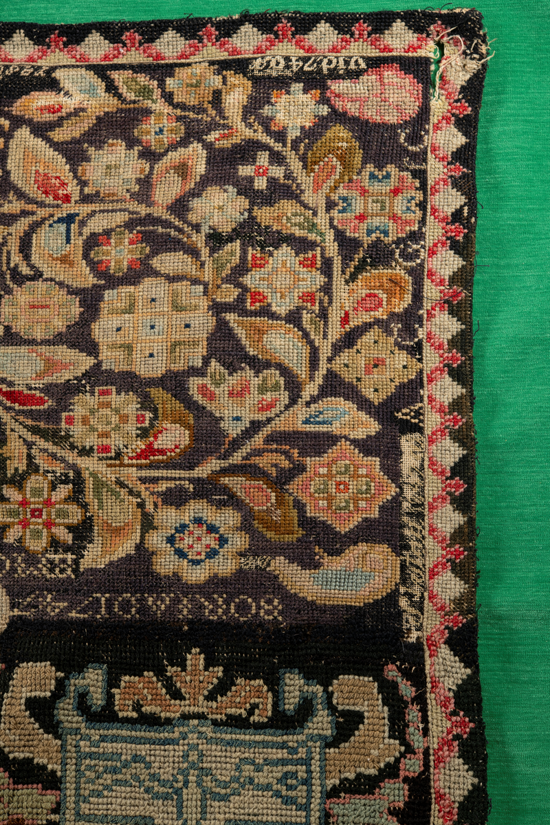 Linbotten med broderier i framför allt ull. Vissa detaljer troligen gjorda i silke. Lagningarna utförda i ull och bomull. Broderiet gjort i korsstygn. De äldsta delarna (bården) är gjorda i olika stora stygn varför ytans karaktär varierar. Mönster som påminner om pompeijansk stil med bland annat kartusher, urnor och växtornament. Mittpartiet inramat med roccaier eller akantusblad, blombotten med liljor och rosor samt vinrankor. Längst ena långsidan även inslag av korall. Hörn med spiralformade blomstergirlanger, dessa med drag av folkligt broderi.
Brunsvart botten, ojämt blekt. Merparten beigegröna nyanser på växtornamenten. Blåa och röda inslag där vissa röda delar skulle kunna vara anilinfärg, troligen i övrigt växtfärg.