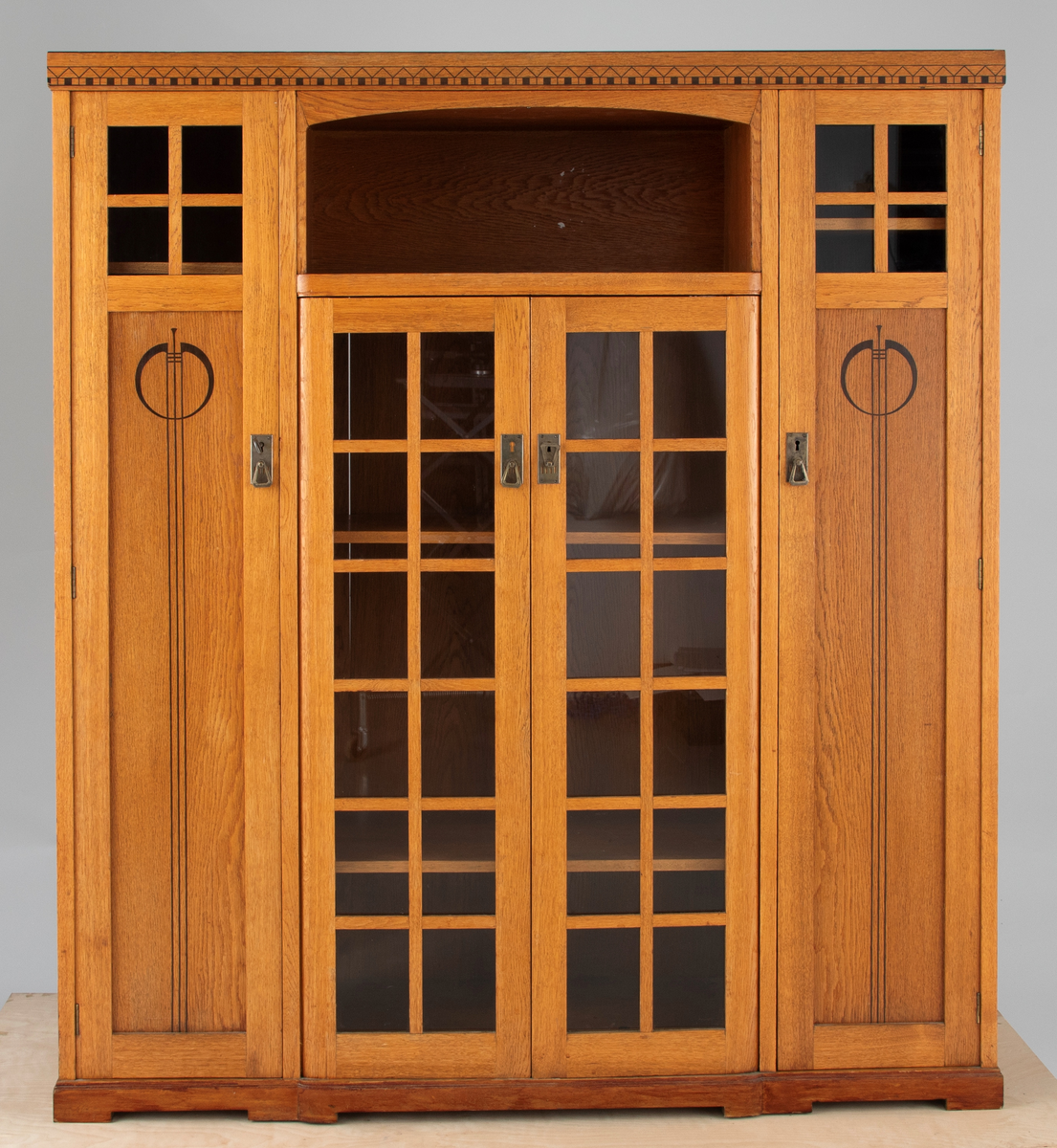 Buffet i bonet eik, dekorert med intarsia av ibenholt (?) og messingbeslag. Møblementet har en streng arkitektonisk oppbyggning, og preges av et spill mellom vertikale og horisontale volumer. Midtpartiet består av et vitrineskap med dobbeltdører, dekorert med felt av krysspostvinduer. Det rektangulære overskapet har svakt buet innramming. På hver side av midtpartiet to smale vertikale skap, hvis dører er dekorert med intarsia i form av geometriske jugendornamenter. Buffeten avsluttes med et profilert toppstykke.