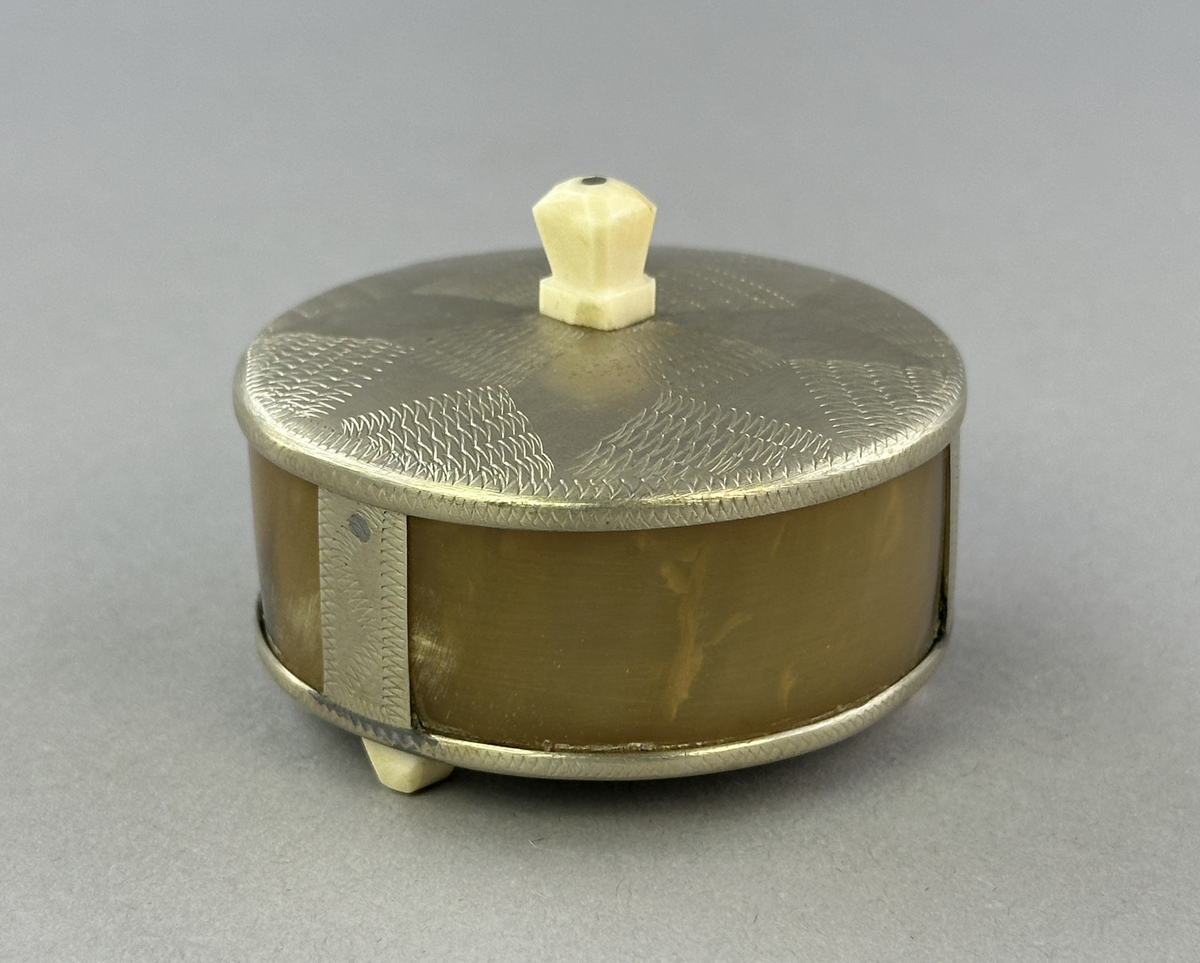 Saltkar, i form av rund burk med lock, i silversmide utfört av resandefolk. Metall i botten och lock med graverat mönster. Kohorn mellan botten och lock, ben i fötter och knopp. Till saltkaret hör en sked, se inv.nr 0875.