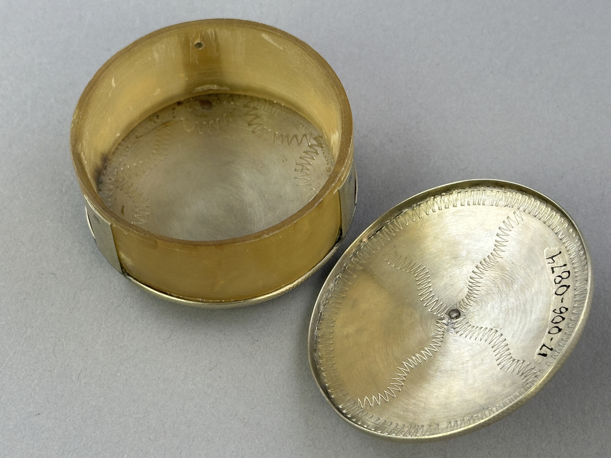 Saltkar, i form av rund burk med lock, i silversmide utfört av resandefolk. Metall i botten och lock med graverat mönster. Kohorn mellan botten och lock, ben i fötter och knopp. Till saltkaret hör en sked, se inv.nr 0875.