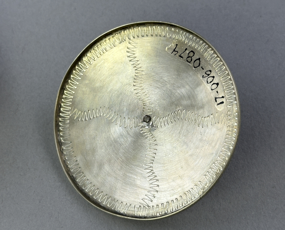 Saltkar, i form av rund burk med lock, i silversmide utfört av resandefolk. Metall i botten och lock med graverat mönster. Kohorn mellan botten och lock, ben i fötter och knopp. Till saltkaret hör en sked, se inv.nr 0875.