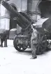 Foto av tandläkare Gunnar Högberg ståendes bredvid en stor kanon, troligen ett artilleripjäs, troligen på Musée de lÁrmée i Paris, 1921.