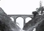 Foto av en järnvägsviadukt som går över en strandväg som leder ner till stranden, 1921.