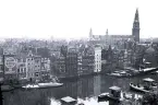 Vy över en kanalstad, troligen Amsterdam i Nederländerna, med flera byggnader längs vattnet och båtar i kanalen, 1924.