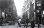 Foto av ett kvarter i, troligen Amsterdam, med människor i rörelse, 1924-25.