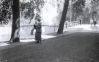 Foto av en kvinna som står vid en kanalkant, troligen i Amsterdam, 1924-25.