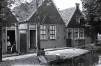 Foto av traditionell holländsk arkitektur, med sina rad-hus som kantar vattendrag och gränder, en typisk byggnadsstil som dominerade under 1900-talet med en kvinna som sitter vid vattnet, 1924-25.
