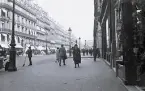 Foto av en gata i Paris med byggnader och strosande människor, 1924-25.