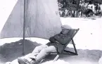 Foto av tandläkare Gunnar Högberg sittande i en strandstol under ett parasoll någonstans på franska atlantkusten, 1924-25.