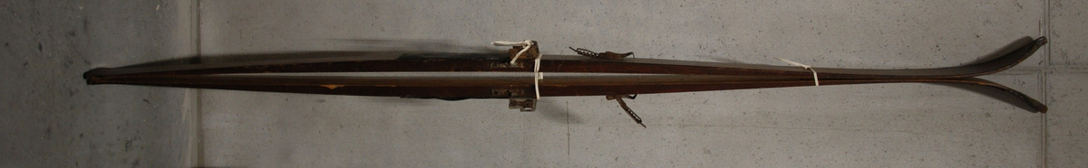 Hoppski. Innsvinger (svakt), 3 kiler underside. Flat overside. Rett avskåret bakende. Spiss på tupp. Kandahar-bindinger, gummisåle.