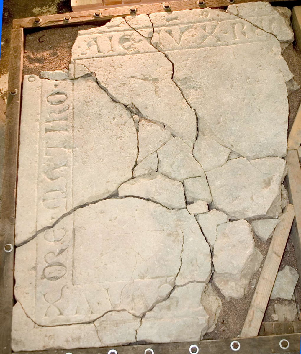 Gravhäll, i flera delar, av kalksten. 
Gravhällen är sannolikt från 1300-talet. Större delen av inskriften saknas. Del av inskriften: --- SVA . VX / ORE . MATIKO (?) SAMT ANIME . CVM . X (=CHRISTO) . REQVESCAT ---.  I översättning: "--- hans hustru---" samt "--- deras själar vila i frid---". Namnen på mannen och hustrun som begravdes saknas, även årtal saknas. Texten MATIKO kan eventuellt vara hustruns namn.