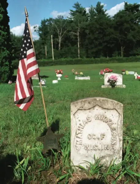 En kirkegård med gravstein. Et amerikansk flagg er plantet i bakken til venstre. Flere gravsteiner i bakgrunn.