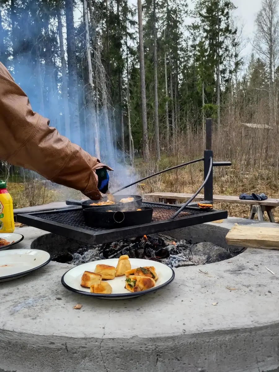 Matlagning vid öppen eld med tallrik med mat i förgrunden.