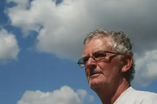 Mann med grått hår og briller. Himmel i bakgrunn 