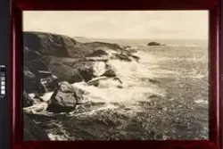 Et sommerlandskap ved kysten, med hav som slår mot svaberg o