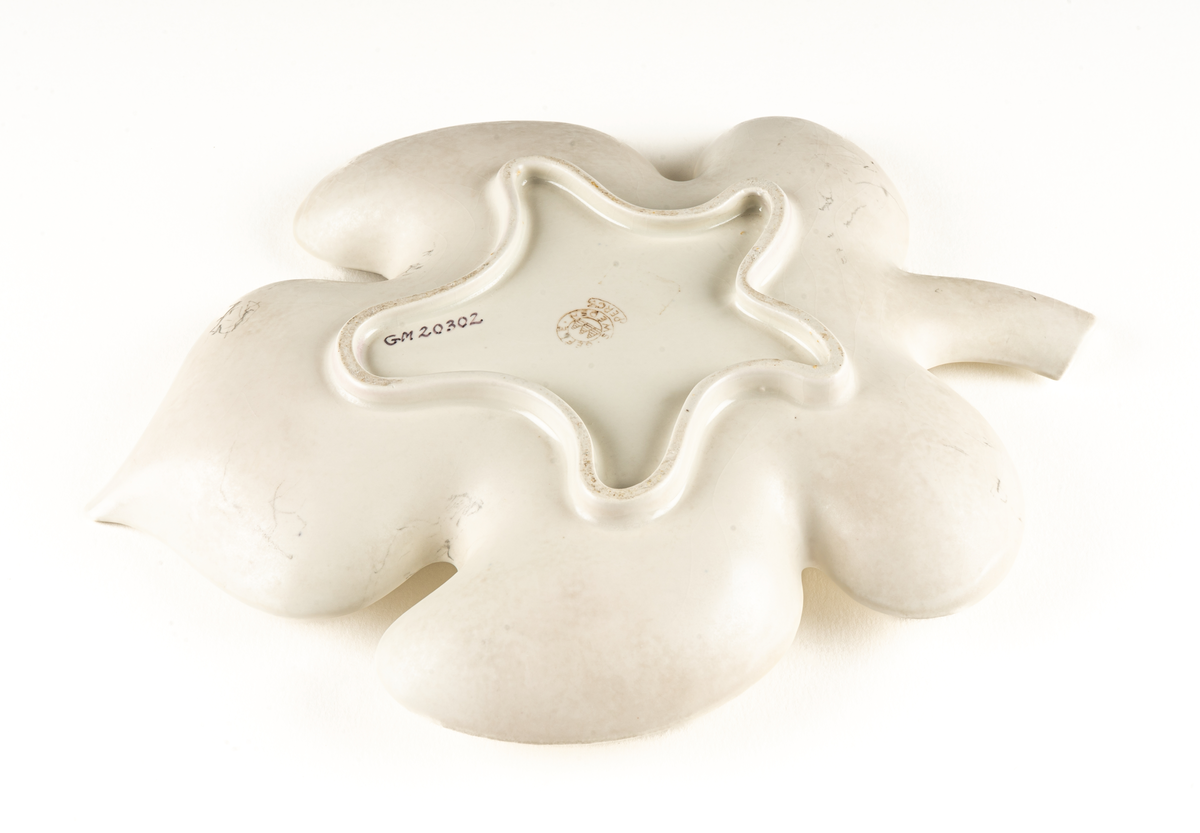 Saladjär av flintgods, modell -EB eller -YT, formgiven av Arthur Percy för Gefle Porslinsfabrik. Skålat, stiliserat lönnlöv med svängd stjälk, femflikigt. Femflikig fotring. Dekor, ljusgrön ton på ovansidan mot vit glasyrfond. Brun skorstensstämpel under med text "Gefle Sweden Percy".