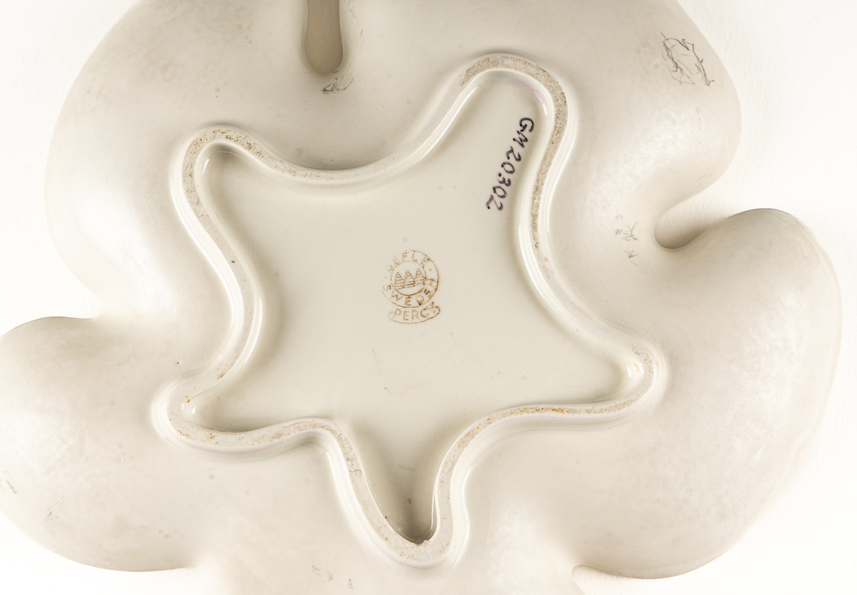 Saladjär av flintgods, modell -EB eller -YT, formgiven av Arthur Percy för Gefle Porslinsfabrik. Skålat, stiliserat lönnlöv med svängd stjälk, femflikigt. Femflikig fotring. Dekor, ljusgrön ton på ovansidan mot vit glasyrfond. Brun skorstensstämpel under med text "Gefle Sweden Percy".