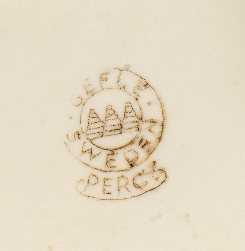 Saladjär av flintgods, modell -EB eller -YT, formgiven av Arthur Percy för Gefle Porslinsfabrik. Skålat, stiliserat lönnlöv med svängd stjälk, femflikigt. Femflikig fotring. Dekor, ljusgrön ton på ovansidan mot vit glasyrfond. Brun skorstensstämpel under med text "Gefle Sweden Percy".