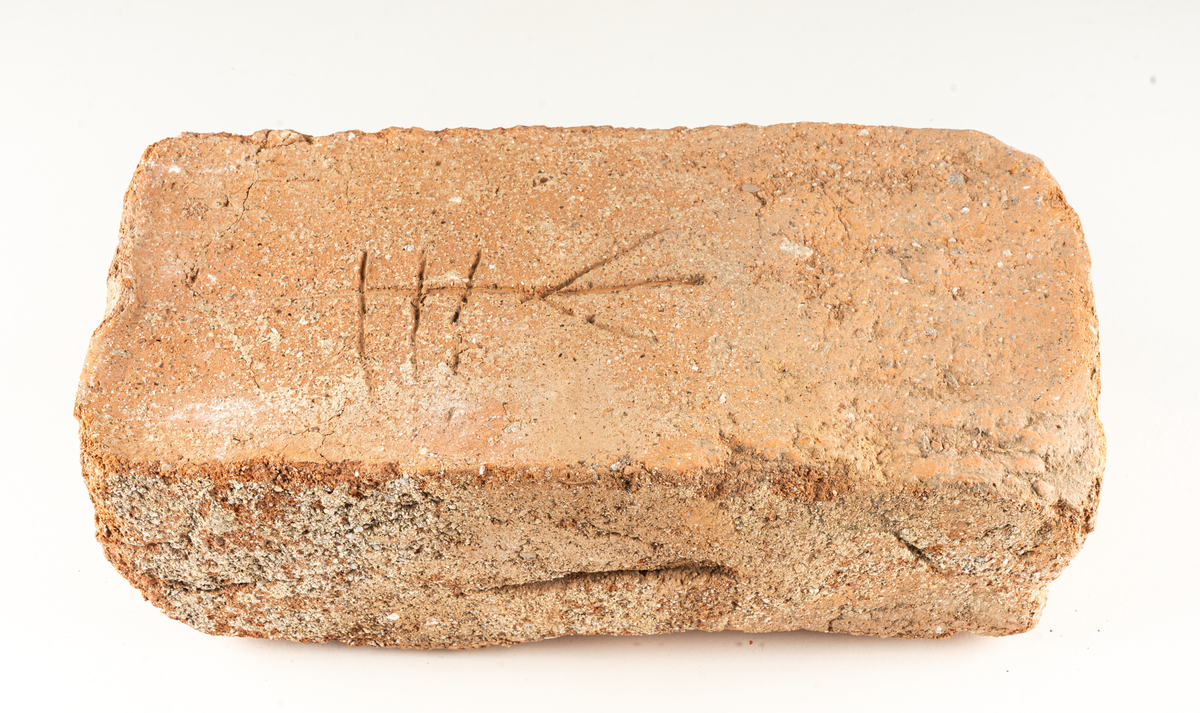 Medeltida tegelsten med bomärke.