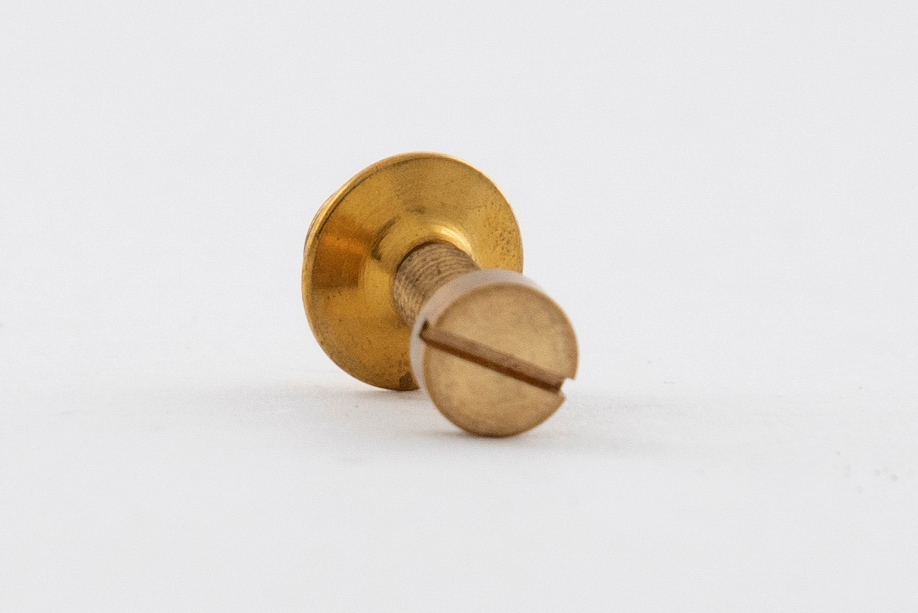 Smykke i eske med bok og folder. En kvadratisk svart eske inneholder et smykke, en bok og en folder. 

Esken har en opptrekksnøkkel preget på lokket.
Smykket er en forgylt pin i form av en skrue. Det er festet på innsiden av lokket.
Bokenhar svart pappbind med "Sigurd Bronger" preget på forsiden. Den har 103 sider, norsk og engelsk tekst, farge- og svart-hvit fotos.
Folderen er i tynn, gråmelert kartong med en opptrekksnøkkel tegnet på forsiden. Den inneholder Sigurd Brongers CV.